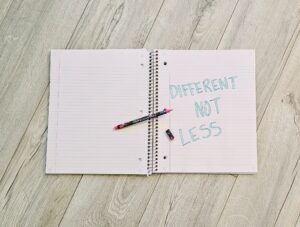 Open notebook with a written affirmation, “Different, not less.